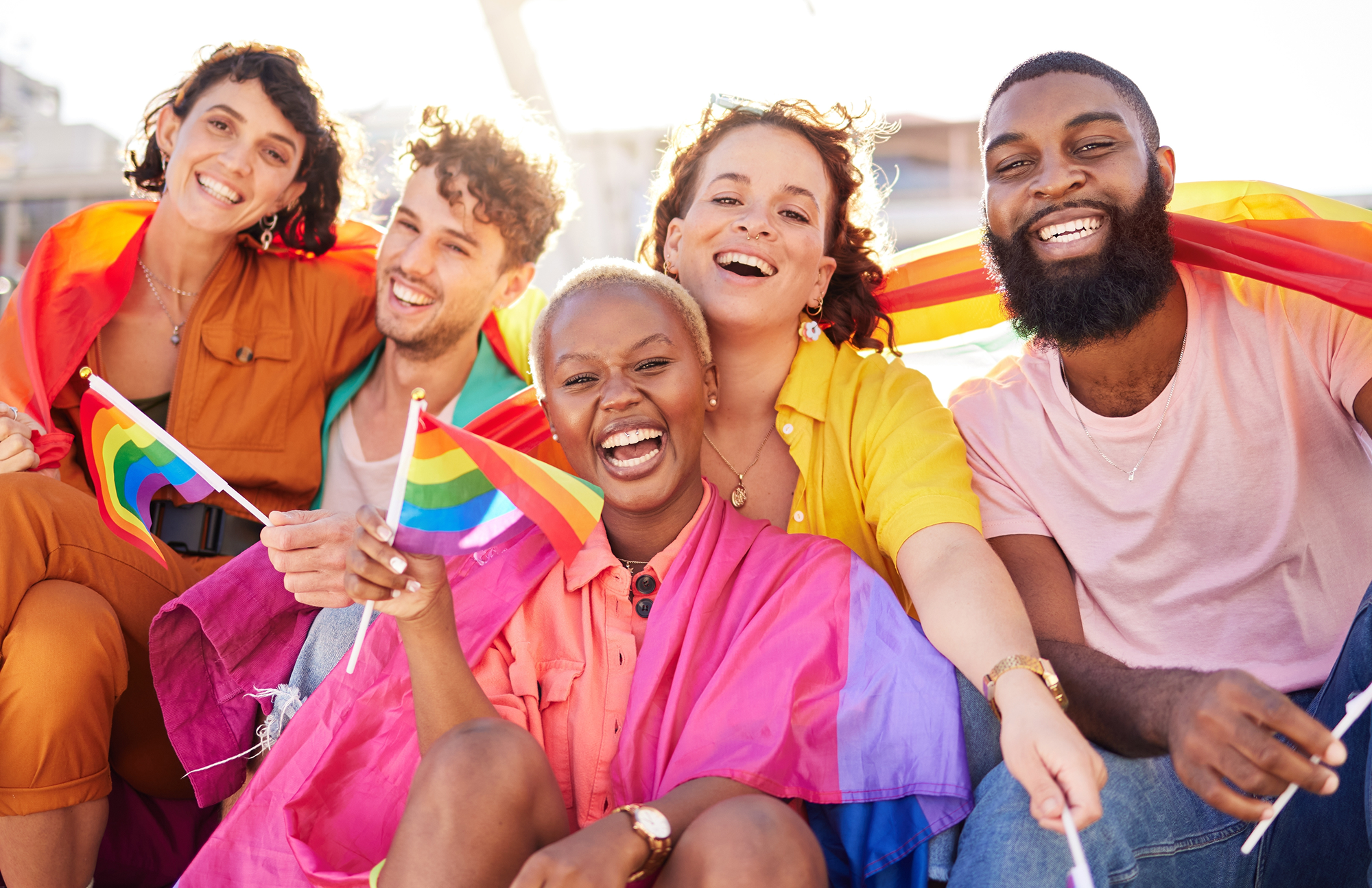 A joyful group celebrating with Pride flags and smiles.